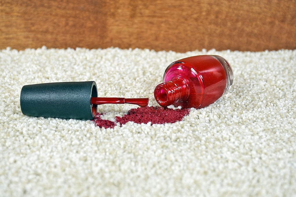 Close up of bright red nail polish on light colored carpet