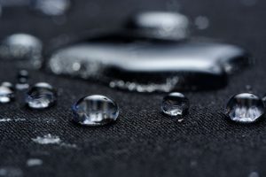 Macro of water drops on black waterproof fabric